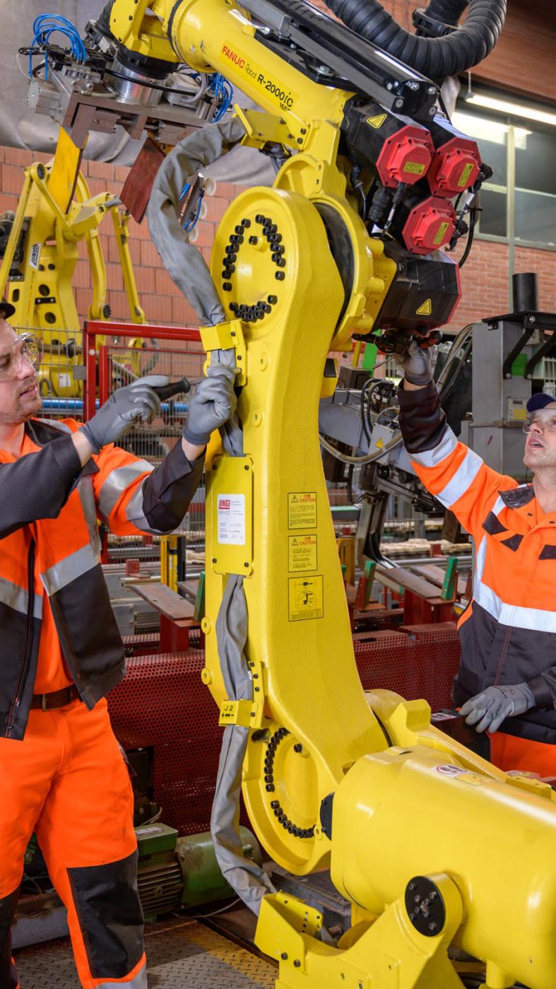 two men working on a robot in a factory