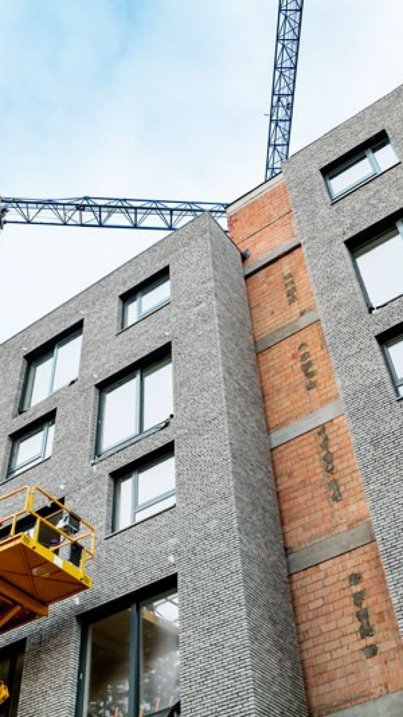 Brick building under construction, blue cranes
