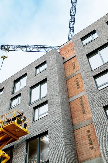 Brick building under construction, blue cranes