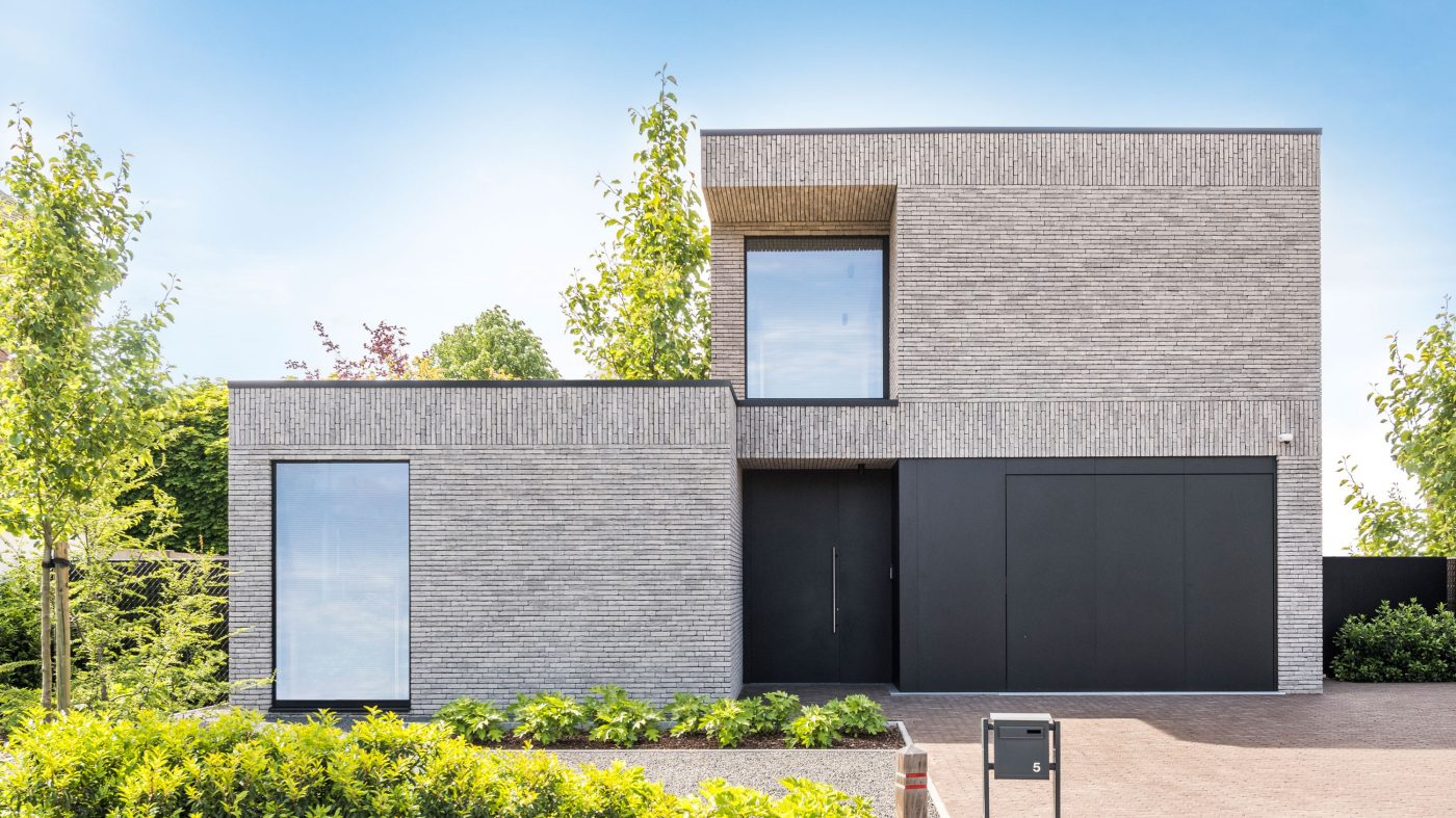 House with brick facade, dark gray front door, trees