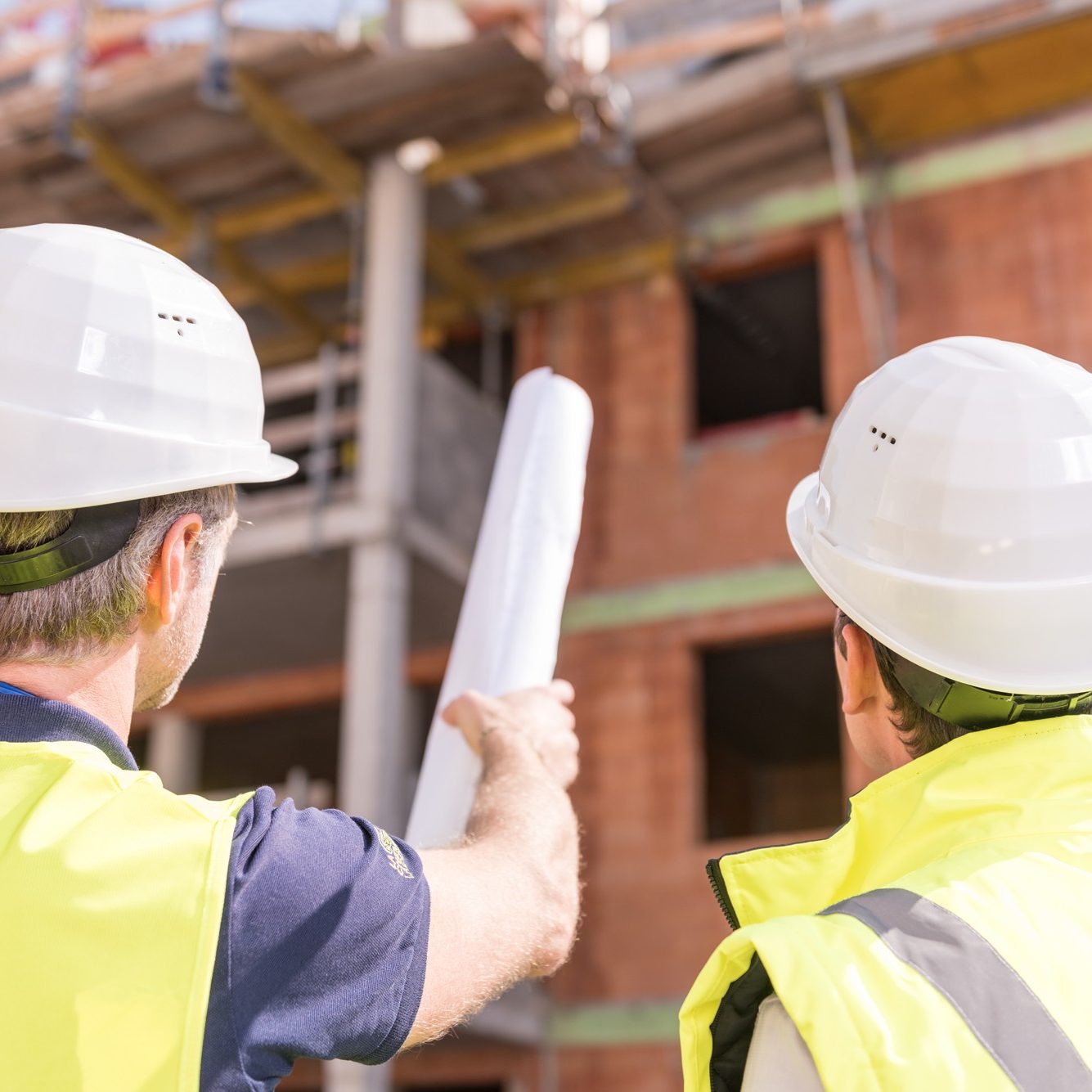 Builder pointing at building shell with blueprint