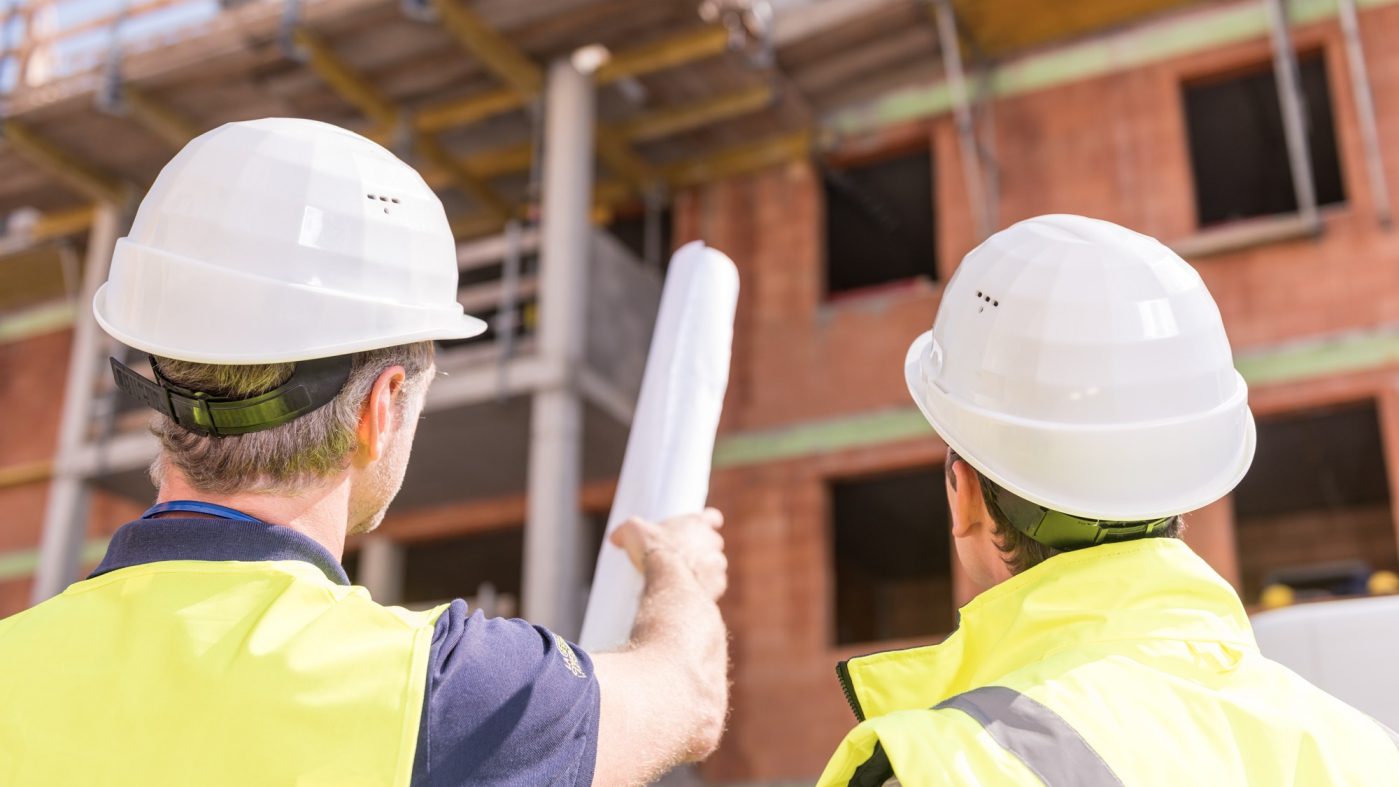 Builder pointing at building shell with blueprint