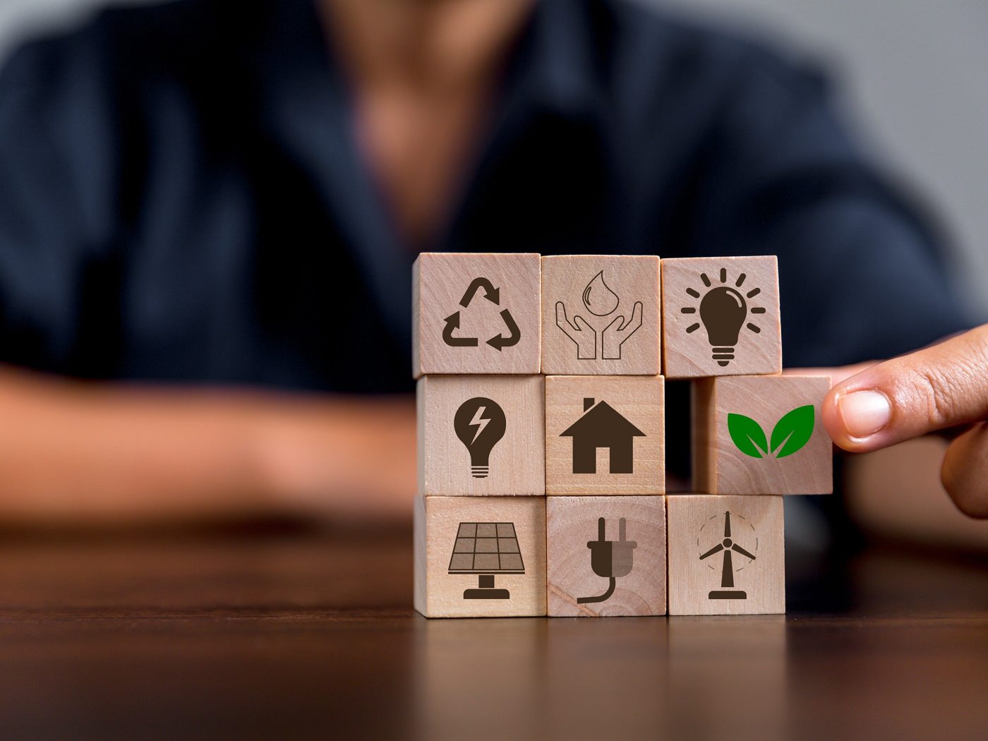 Person with wood cubes, with sustainable symbols