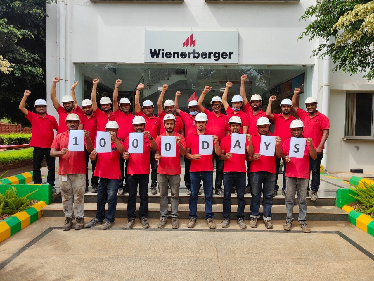 Group of people in red shirts and with white helmets celebrating 1000 days without accident