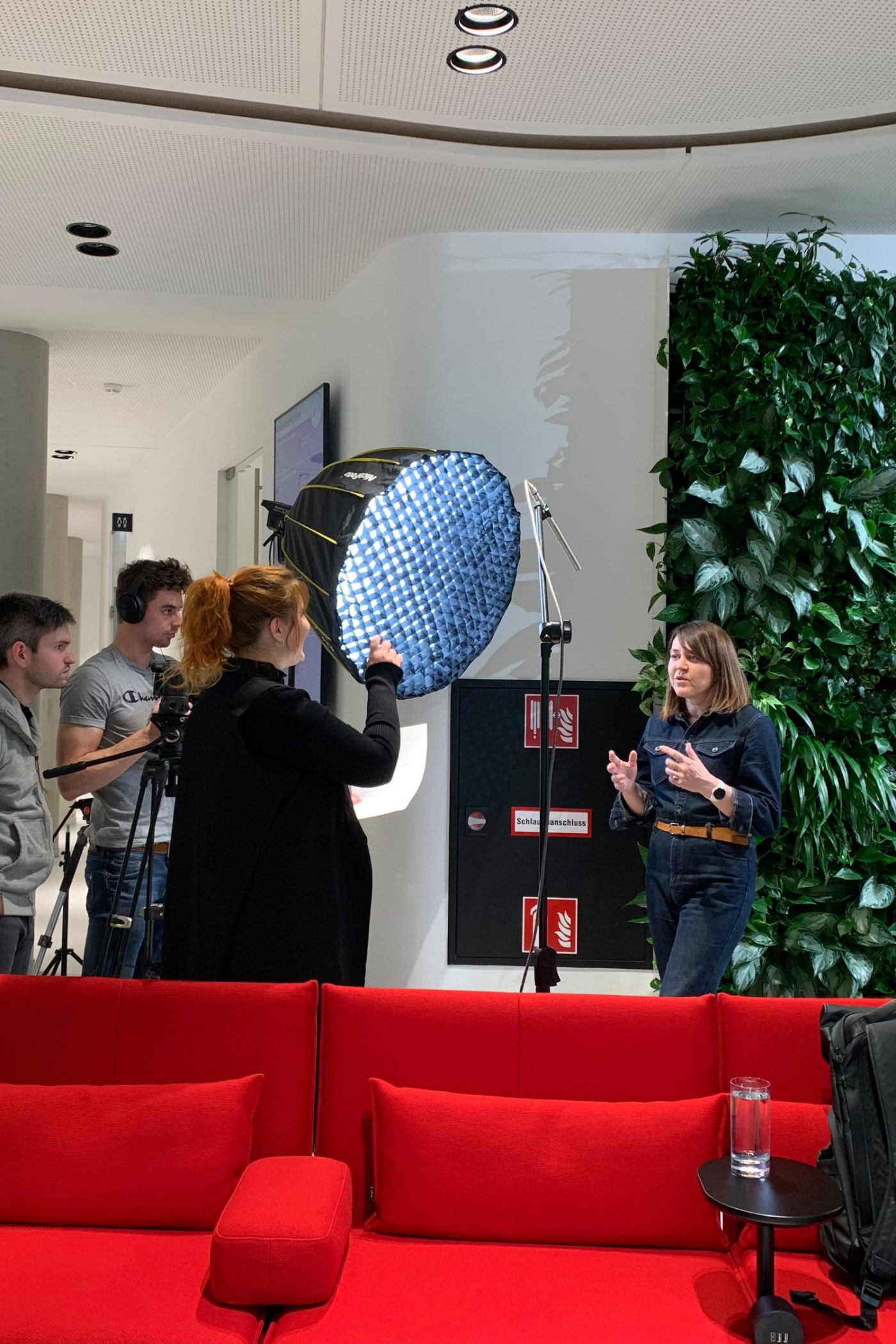 video shoot, four people, women speeks, red couch, plant wall