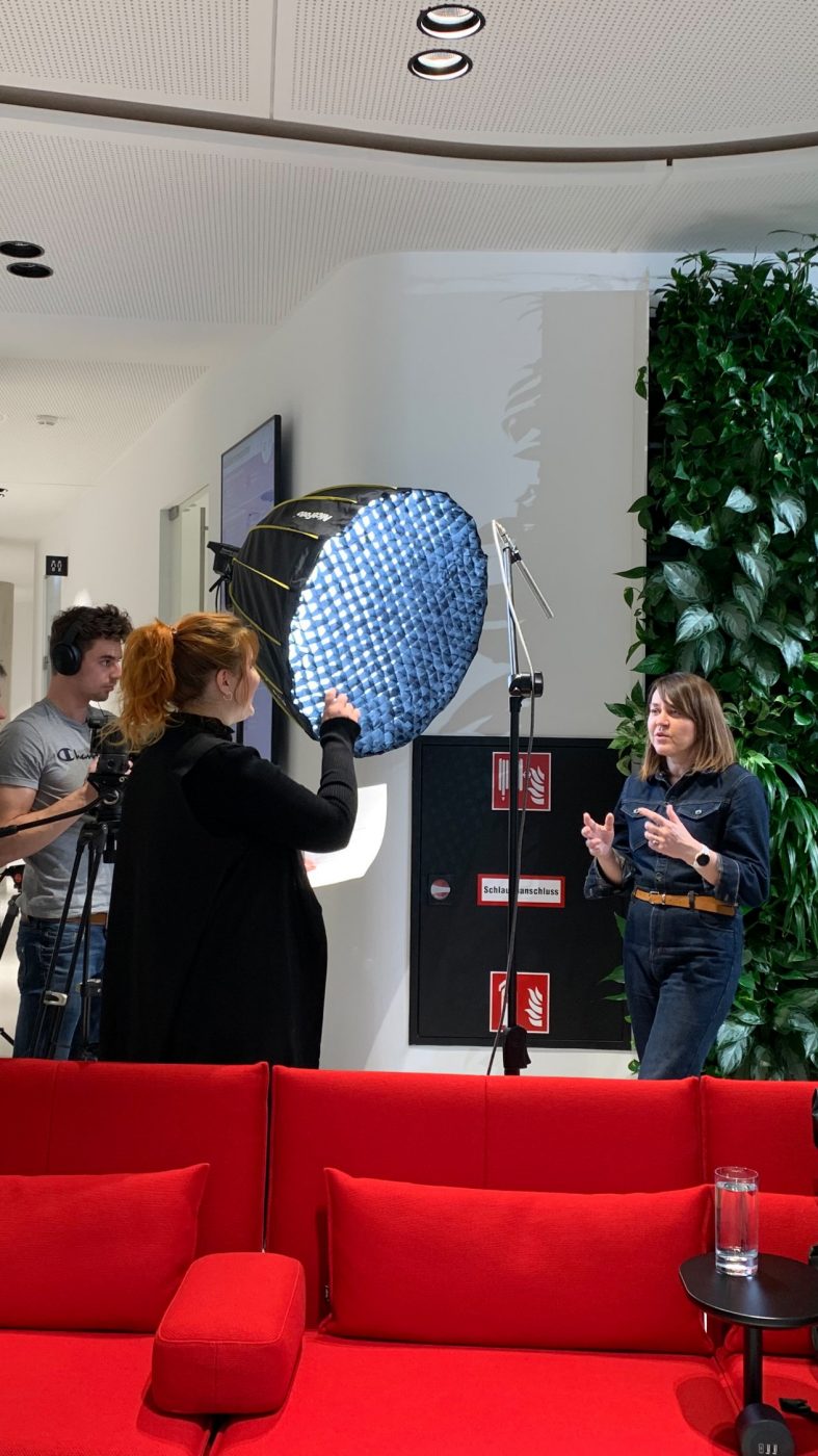 video shoot, four people, women speeks, red couch, plant wall