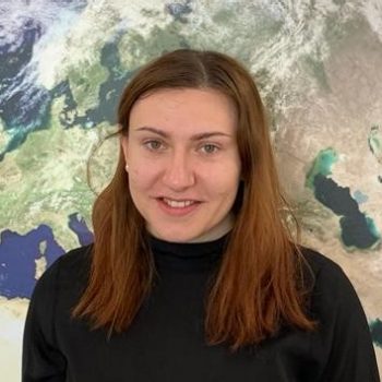 Woman infront of a wall with illustration of the earth