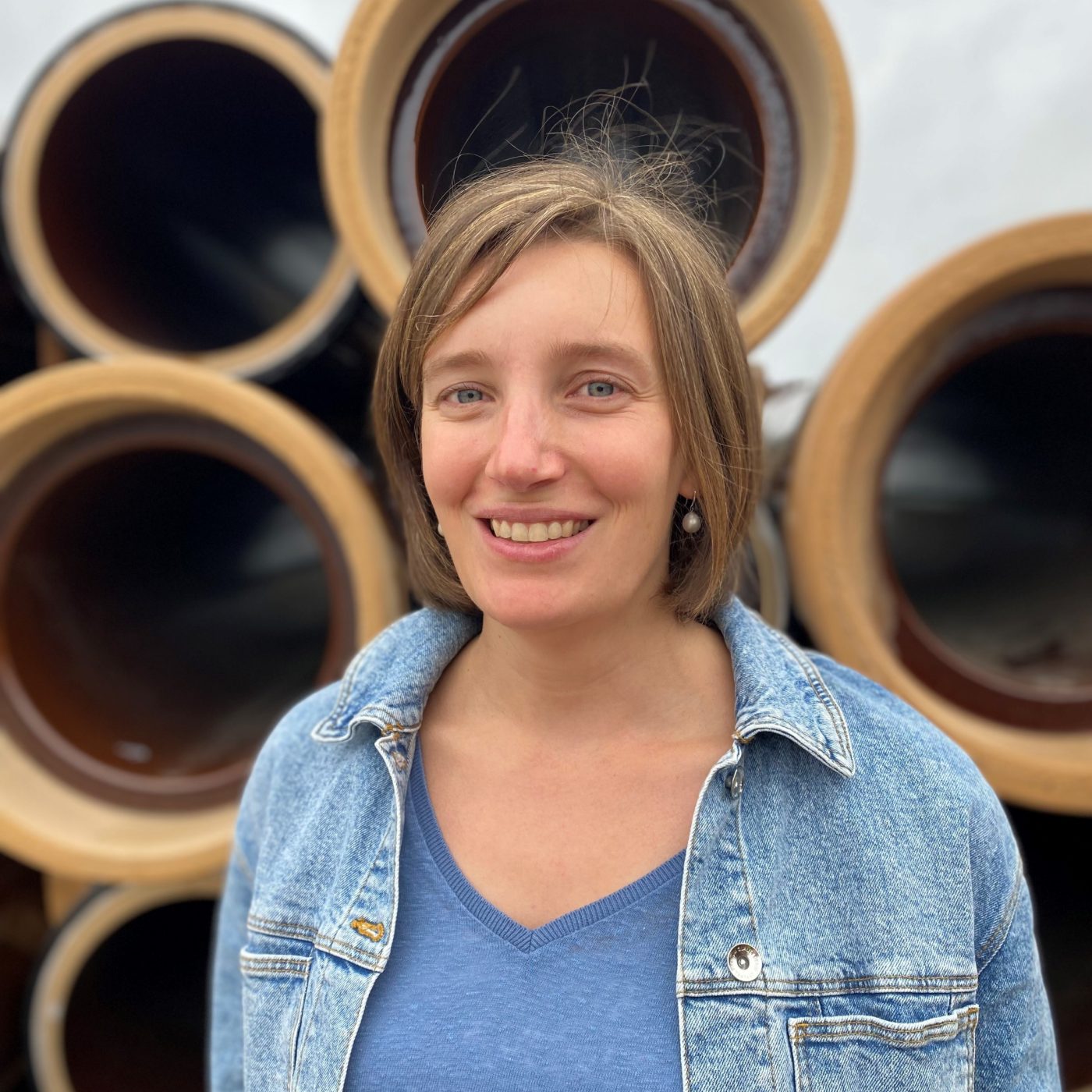 Woman laughing at camera, standing in front of ceramic pipes