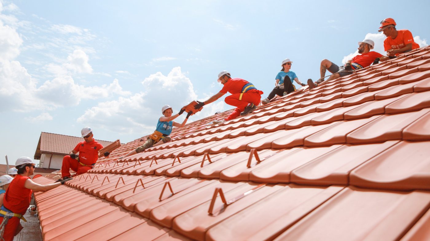 People cover a roof with tiles, blue sky