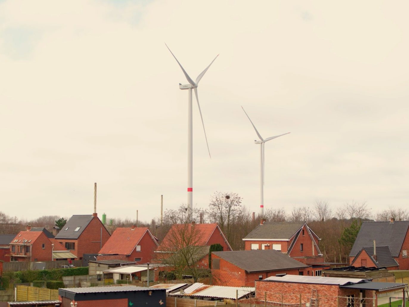 Two wind turbines behind houses