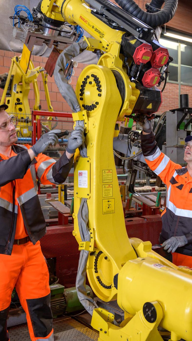 two men working on a robot in a factory