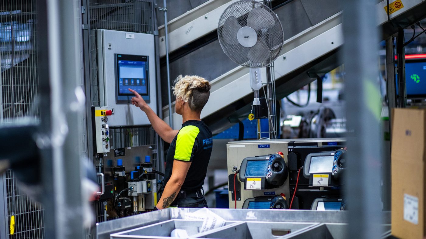 Woman in a factory operating a machine via a touchscreen monitor