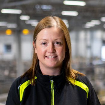 Woman in a factory building smiling into the camera